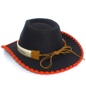Detail of black cowboy hat with red stitched brim and bohemian decorative band buckle