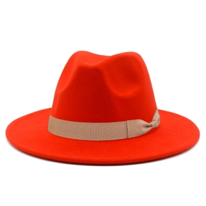 Detailed close-up of a bright red fedora hat with a beige grosgrain ribbon and bow accent