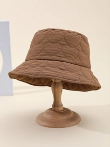 Detail of dark brown quilted bucket hat with heart embroidery on wood display