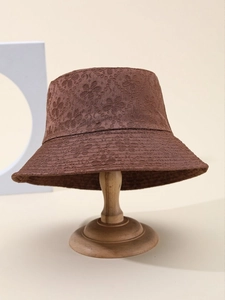 Detailed close-up of dark brown bucket hat with floral lace embroidery and hollow texture