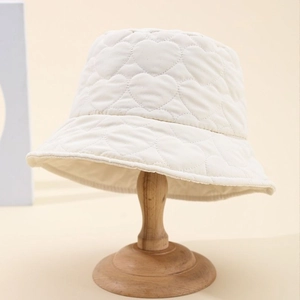 Off-white heart quilted bucket hat for women on a wooden stand for autumn and winter