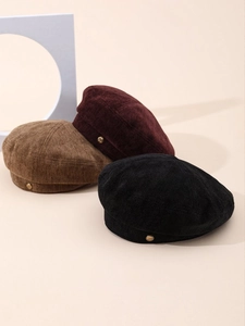 Detailed close-up of corduroy beret set in black, wine red, and brown with gold buckles
