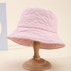 Light pink puffer bucket hat with heart quilted patterns on a wooden display stand