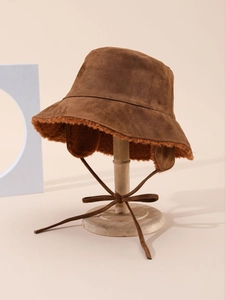 Detail of brown suede bucket hat showing thick beige faux shearling lining and drawstring