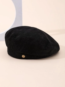 Detail of black herringbone corduroy beret featuring a gold L'AMOUR metal emblem
