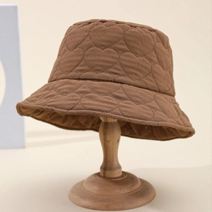 Brown heart-pattern quilted bucket hat for women on vintage wooden stand