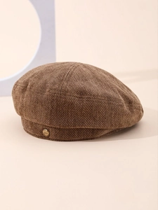 Detail of dark brown herringbone corduroy beret with a gold L'AMOUR engraved metal button