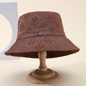 Brown bucket hat with floral embroidery on wooden stand, stylish outdoor sun protection cap