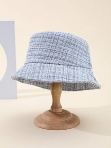 Close-up of light blue tweed bucket hat showing textured woven plaid on a wooden stand