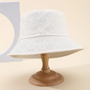 Elegant ivory bucket hat with floral lace embroidery on wooden stand for outdoor fashion