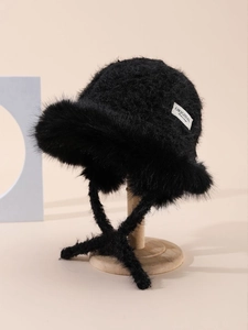 Detail of black faux fur bucket hat featuring side fashion label and long straps