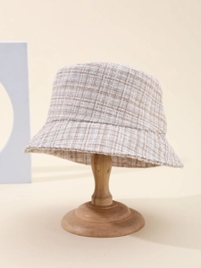 Detailed macro view of the beige plaid pattern and tweed fabric of this bucket hat