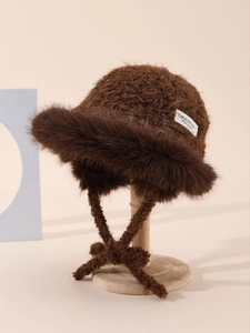 Close-up of brown knit bucket hat with plush fur trim and fashion design label detail