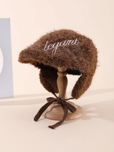 Detail of dark brown plush earflap hat with elegant embroidery on soft faux fur fabric