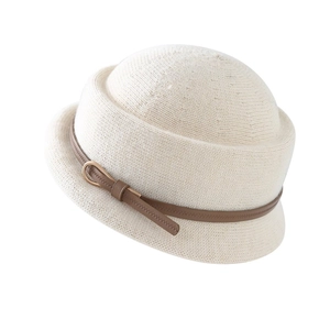 Détail d'un chapeau cloche en maille beige avec bride en cuir marron et boucle dorée
