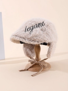 Detailed view of beige fleece earflap hat with elegant embroidery and side straps