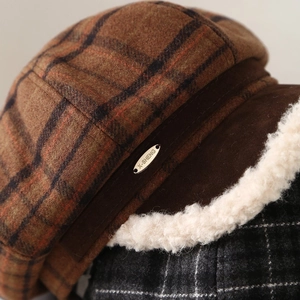 Detail view of vintage plaid beret with plush faux lamb wool trim and metal brand plate