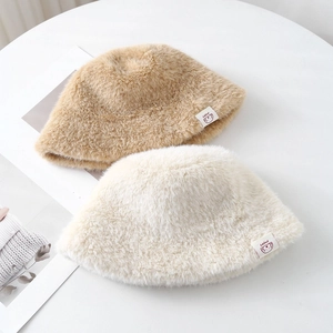 Close-up of soft plush bucket hats in khaki and beige with cute puppy woven labels