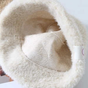 Detailed close-up of soft off-white plush bucket hat lining and woven brand label