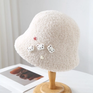 Detail of cream plush bucket hat featuring cute teddy bear and heart embellishments