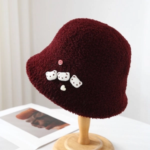 Detail of burgundy plush bucket hat with cute bear patches and soft faux lamb wool texture