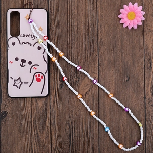 Handmade beaded phone strap with colorful heart charms and white seed beads on wood background