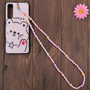 Handmade pink beaded phone strap with colorful heart charms on a wood background