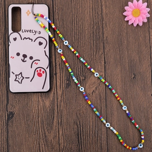 Handmade beaded phone strap with colorful rice beads and evil eye charms on wood