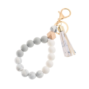 Detail of beaded keychain bracelet with silicone beads, wooden bead, and marble leather tassel