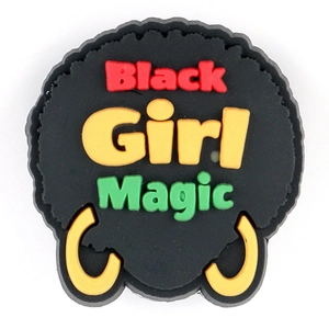 Macro shot of Black Girl Magic PVC shoe charm with vibrant yellow earring detail