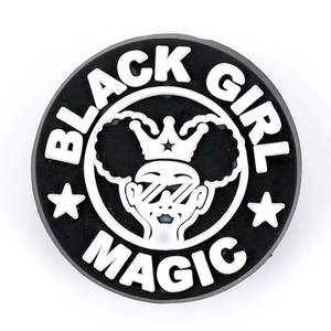 Macro shot of circular PVC shoe charm with Black Girl Magic lettering and crown