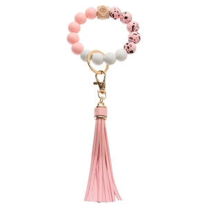 Detail of pink leopard silicone beads and wooden eye bead on a tassel keychain bracelet