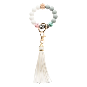Detail of wooden hexagonal bead with Evil Eye engraving and white leather tassel on keychain