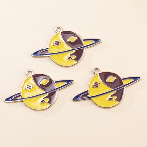 Detailed macro of three yellow Saturn-shaped enamel charms for DIY jewelry making