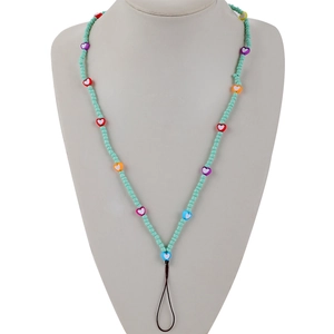 Detail of handmade beaded phone strap with green seed beads and colorful heart charms