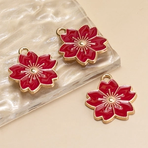 Detailed close-up of three red enamel cherry blossom charms with gold alloy base and rings