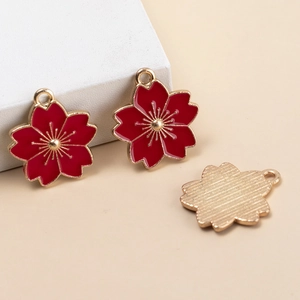 Close-up of red cherry blossom alloy charms with gold edges for DIY jewelry making