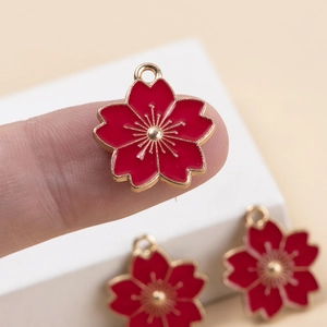 Macro shot of red cherry blossom enamel charm with gold plating for DIY jewelry making