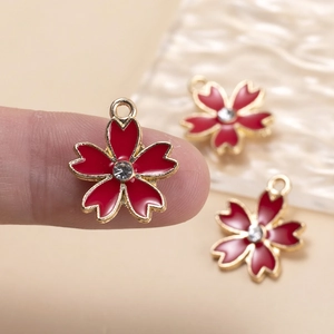 Macro view of small red cherry blossom flower pendant charm with a crystal center