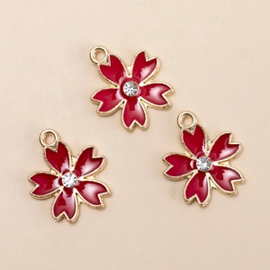 Three deep red cherry blossom alloy pendants with rhinestones on a beige background