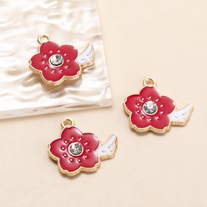 Detailed macro view of red enamel flower charms with white wings and clear central zircon