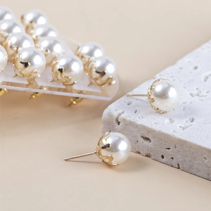 Macro-opname van vintage parel oorknopjes met gouden bloembasis op witte getextureerde steen