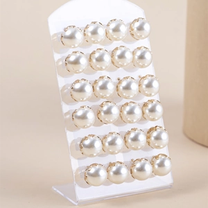 Detail van 12 paar elegante pareloorbellen met goudkleurige klauwzetting op display