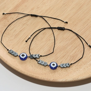 Détail de deux bracelets tissés noirs avec perles œil bleu et breloques en flèche