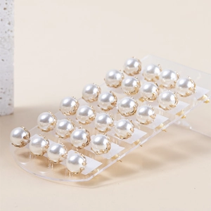 Close-up van 24 paar witte pareloorbellen met gouden zetting op een displaystandaard