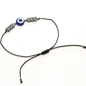 Détail macro du bracelet tressé réglable avec perle d'œil bleu et flèches métalliques