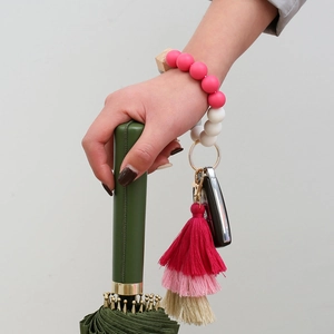 Detail of pink silicone bead bracelet with multi-layer tassel and gold keychain ring