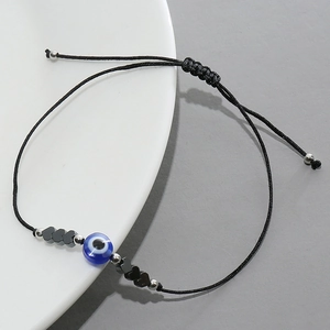 Bracelet œil maléfique tressé ajustable avec perles noires sur assiette blanche