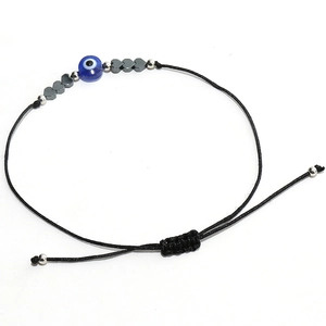 Détail du bracelet tressé ajustable avec œil bleu et breloques en forme de cœur