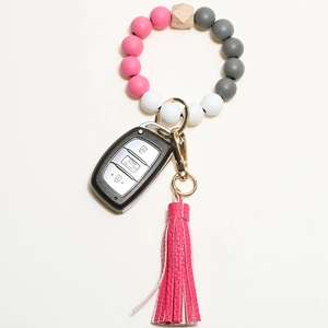 Pink and grey silicone beaded keychain bracelet with wood bead and leather tassel on car key